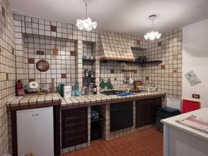 a kitchen with a tiled wall and a counter top at Casetta con camino in centro in Pescasseroli +4 photos