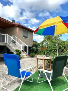 BaltarにあるApartamento Amanecerの椅子2脚、傘1本、テーブル1台