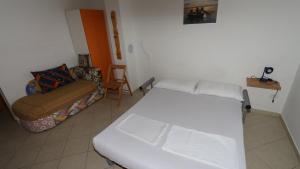 Zimmer mit einem weißen Bett und einem Sofa in der Unterkunft Dugiš studio-no parking in Makarska