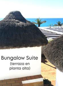 a sign in front of a building with a straw roof at Mandala Bungalows - Adults Only in Los Caños de Meca