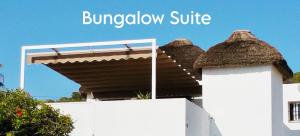 a white fence with a building with a brown roof at Mandala Bungalows - Adults Only in Los Caños de Meca