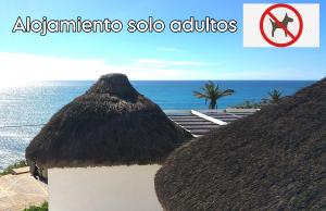 a view of the ocean from between two thatch huts at Mandala Bungalows - Adults Only in Los Caños de Meca