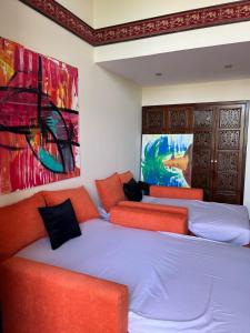 three beds in a room with paintings on the wall at Domina Coral Bay Harem Luxury in Banī Ghālib