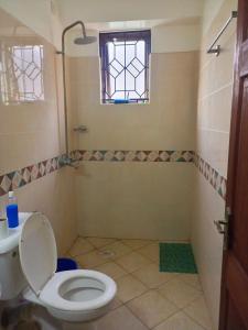 a bathroom with a toilet and a sink and a window at Cozyblue fully furnished 1 bedroom bnb in Mombasa