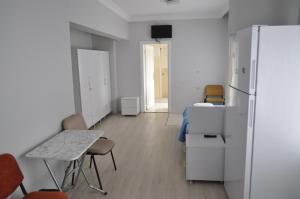 a room with a refrigerator and a table and a bed at BULUT GAYE Pansiyon in Edirne