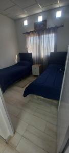 a bedroom with two blue beds and a window at Lam DEPARTAMENTO TEMPORARIO in Resistencia