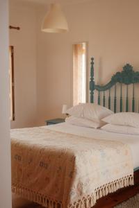 a bedroom with a large bed with white sheets and pillows at Quinta Amarela - B&B in Nazaré