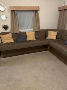 a couch with pillows and a window in a living room at 2 bed caravan seawick hoilday Park in Clacton-on-Sea +2 photos