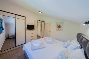 a bedroom with a white bed and a tv at Villa Goranovic in Herceg-Novi