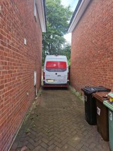 a white van parked in a alley between two brick buildings at 3-Bed Detached House Private Drive for Two Cars in Farsley