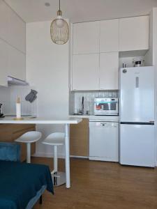 a white kitchen with a table and a white refrigerator at Bel appartement avec vue mer in Le Trayas