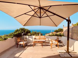 a patio with a table and chairs and an umbrella at Omero in Tindari