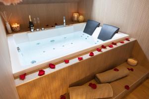 une salle de bain avec une baignoire avec deux chaises et des roses dans l'établissement CEVA Suite Sakura - Jacuzzi & Cinéma Centre ville, à Saint-Étienne