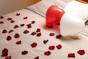 un cœur rouge et des roses sur un lit dans l'établissement CEVA Suite Sakura - Jacuzzi & Cinéma Centre ville, à Saint-Étienne 8 autres photos