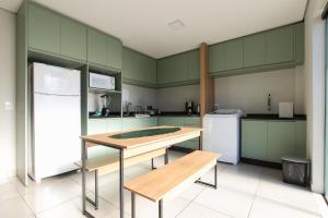 a kitchen with green cabinets and a table and a refrigerator at Lou Suítes 7 - Conforto e Paz in Guarapuava