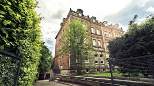 a large brick building with a tree in front of it at Apartmenthaus Königsallee in Bayreuth