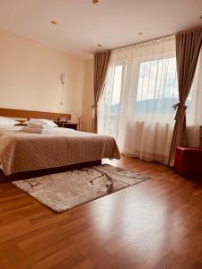 a bedroom with a bed and a large window at Vila Gabi in Buşteni
