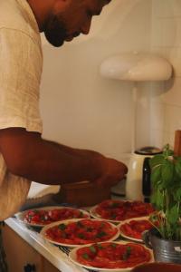a man standing in front of four pizzas on a counter at Quinta Amarela - B&B in Nazaré