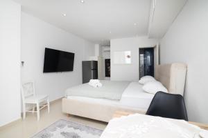 a white room with two beds and a desk and a tv at Dida moj in Senj
