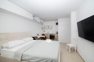 a white bedroom with a large bed and a flat screen tv at Dida moj in Senj