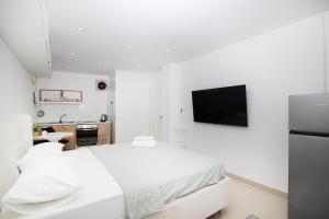 a white bedroom with a bed and a tv on the wall at Dida moj in Senj