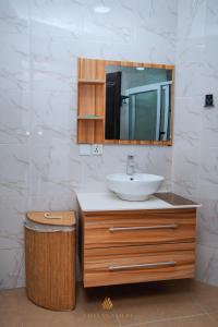 Un baño con lavabo, espejo y cubo de basura. en Chanan Court Apartment, en Accra