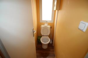 a small bathroom with a toilet with a window at Land's Hause Bungalows par La Conciergerie Française Emplacement 6AB in Pataias