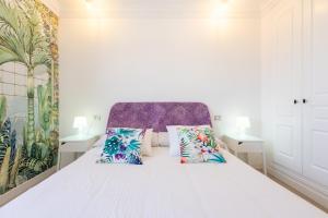 1 dormitorio con cama blanca y almohadas coloridas en El Poris, en Porís de Abona 32 fotos más