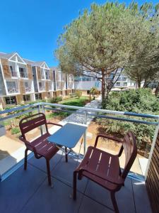 Un patio con dos sillas y una mesa en un balcón. en Thalazur Carnac, en Carnac
