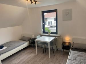 a room with two beds and a table and a window at Pension Hüttengrund in Achim