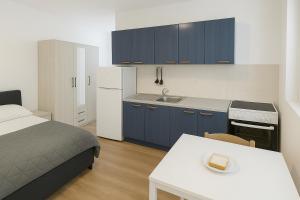 a bedroom with a bed and a kitchen with a table at Apartment Anna-Nikola Igalo in Igalo