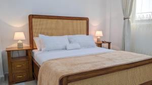 a bedroom with a large bed with two lamps at Kay's Place Zanzibar in Zanzibar City