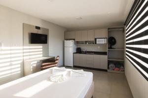 a kitchen with a white bed and a refrigerator at Lou Suítes 11 - City Mood, estadia leve in Guarapuava