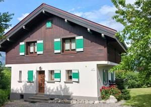 a house with green shuttered windows and a brown roof at Chalet Mireneige, charme et confort face au Mont Blanc in Combloux