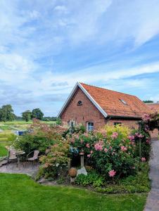 a brick house with flowers in front of it at Ferienhaus Gulfhof Tjaden in Großefehn 