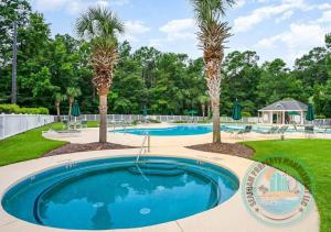 a swimming pool with palm trees in a yard at 2Br 2Ba Condo on Golf Course in Pawleys Island