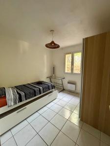 1 dormitorio con cama y mesa en el suelo de baldosa en Charmant bas de villa avec jardin, en La Ciotat 3 fotos más