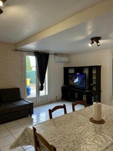 Una sala de estar con una mesa y un televisor. en Charmant bas de villa avec jardin, en La Ciotat