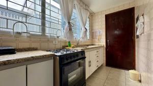 a kitchen with a stove and a sink and a window at Fragata Beach House - A duas quadras do Mar in Guaratuba