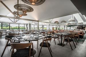 a dining room with tables and chairs and windows at Thalazur Carnac - Résidence in Carnac