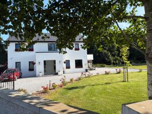 a white house with a garden in front of it at Ashlee Lodge, Shanagarry P25K6R6 Near Ballymaloe Cookery School & Garryvoe Hotel in Shanagarry