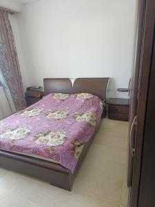 a bed in a room with a purple bedspread at Marwan in Tunis