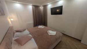 a hotel room with two beds and a flat screen tv at Apartament ROYAL Ełk in Ełk