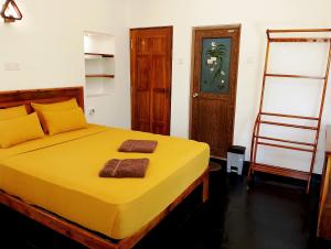 a bedroom with a yellow bed with two towels on it at Milk House Cottage in Udawalawe