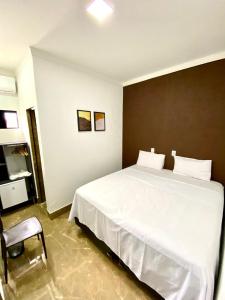 una camera da letto con un grande letto bianco e una sedia di Hotel Uirapuru 02 a Alexânia