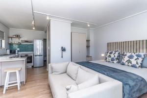 a bedroom with a large bed and a white couch at Stylish Studio with Ocean Views at Wavescapes in Muizenberg