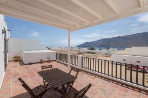 a balcony with a table and chairs and the beach at Lightbooking La Graciosa in Caleta de Sebo