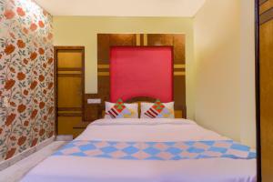 a bedroom with a bed with a red headboard at Hotel O Home Cozy Studio Collage Square Hotel Maya International Near St. Thomas's Church in Kolkata