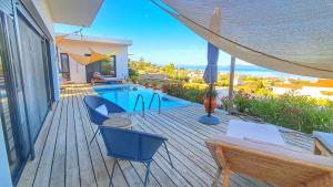 a wooden deck with a swimming pool and a hammock at Villa Karma in Paleros