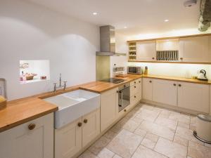 a large kitchen with white cabinets and a sink at Barbican Cottage in Middleham